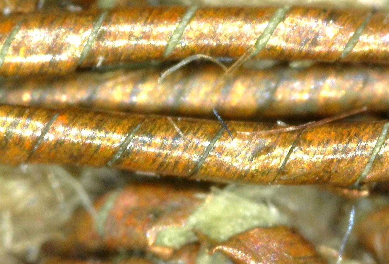 La figura mostra un dettaglio a forte ingrandimento dei fili, con le lamine metalliche che si avvolgono a elica cilindrica attorno alle fibre costituenti il nucleo.
