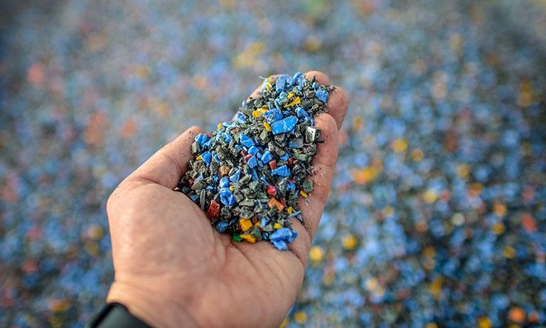 mano che contiene delle microplastiche colorate