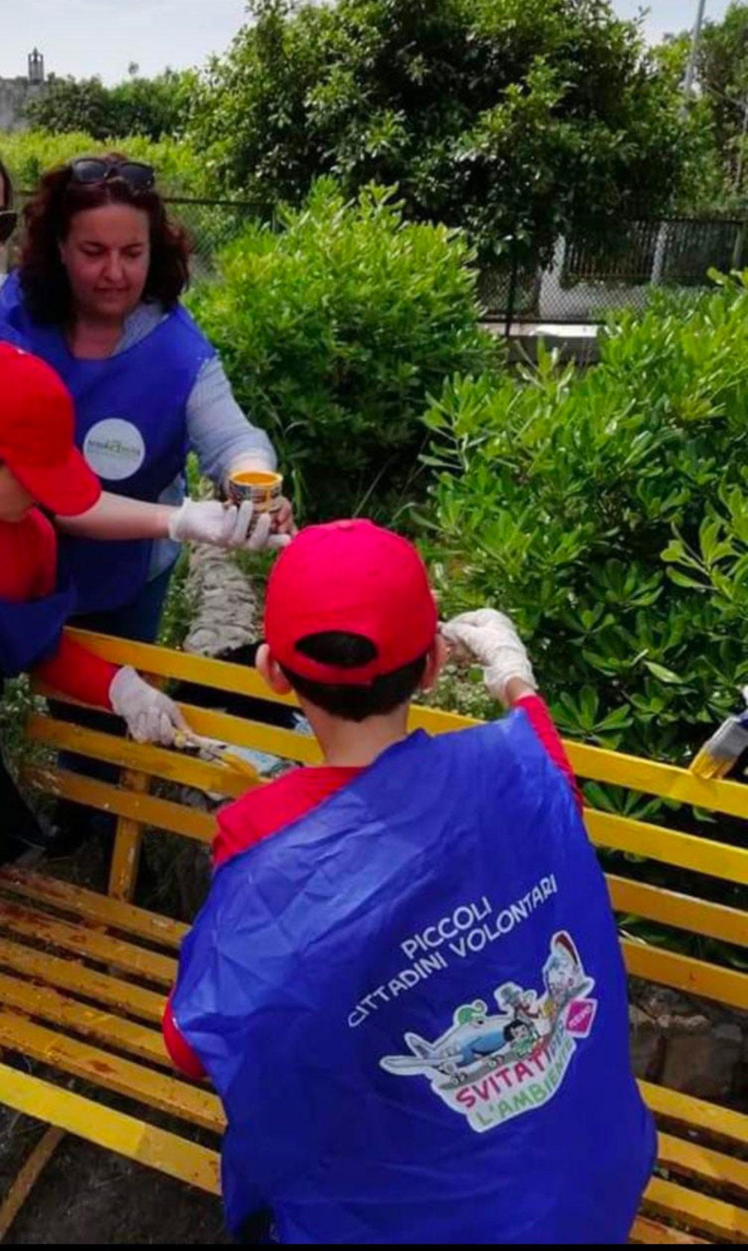 Ragazzi che pitturano una panchina con le insegnanti